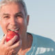older man with dentures biting an apple