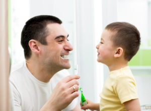 Dad and son brushing teeth together