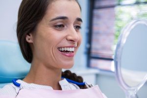 local dentist | patient smiling while looking at mirror.